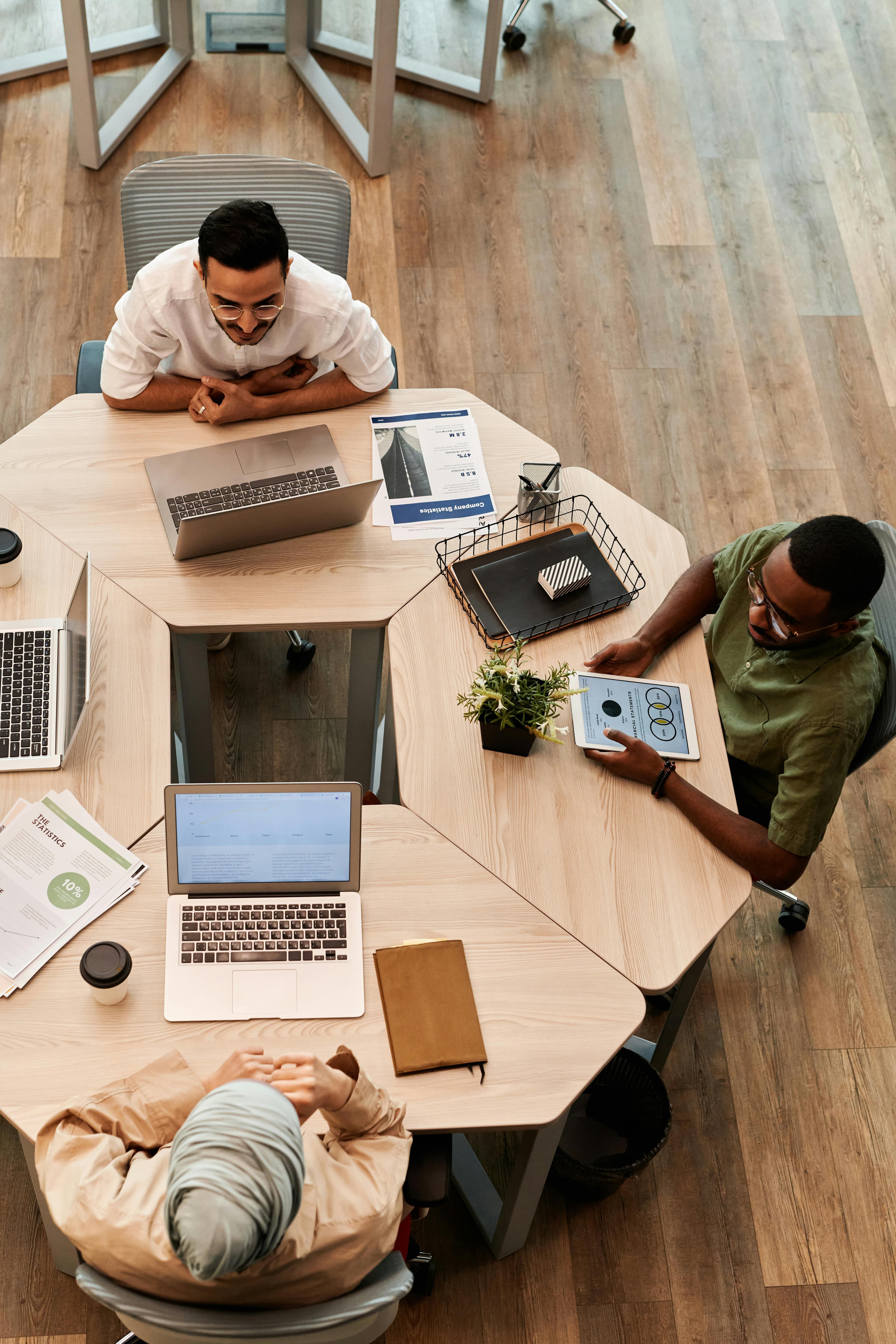 A small team working together at a shared desk, overhead view
